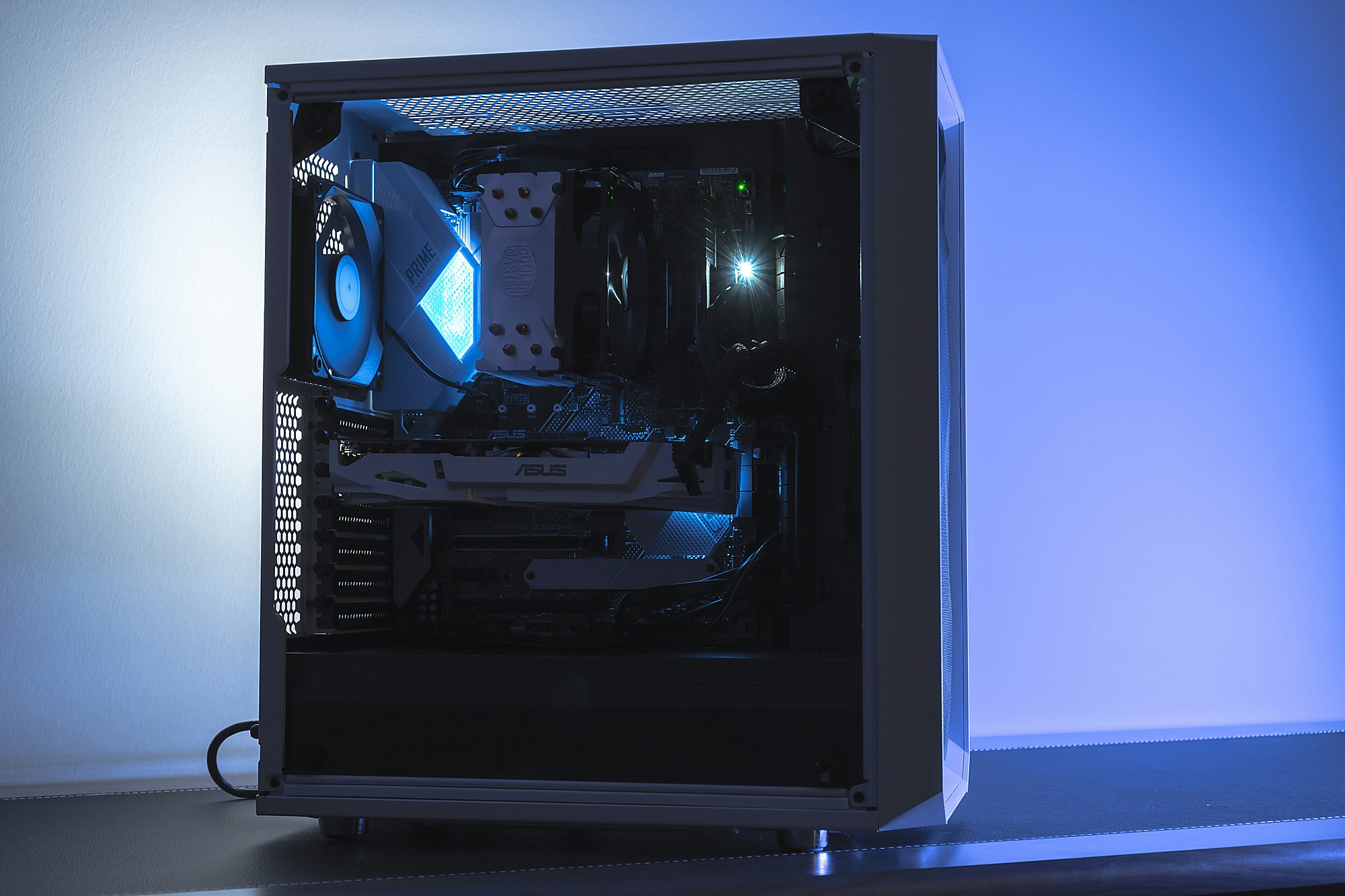 Fertig aufgebauter Computer mit Glasseitenwand und blauer Innenbeleuchtung auf einem Tisch.