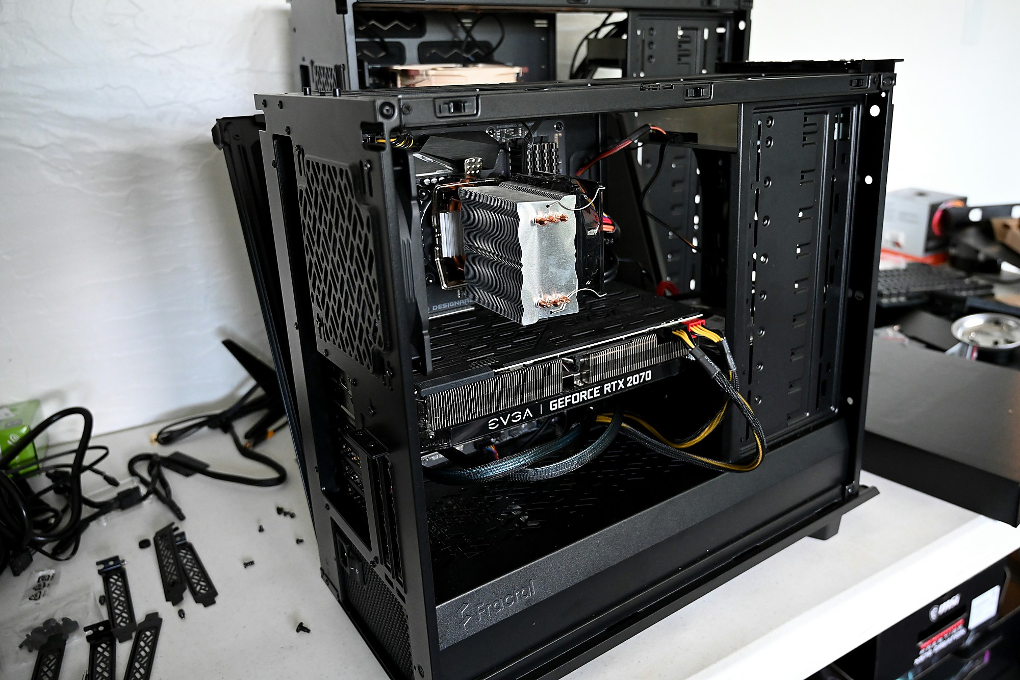 Offener Computer auf der Werkbank während einer Reparatur: Gehäuse mit Grafikkarte, daneben ausgebaute Schrauben und Kabel.